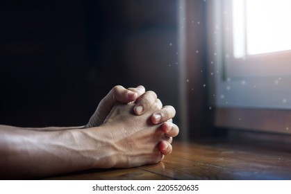 Hands folded in prayer on wooden table with miracle light in church, concept for faith, spirituality and religion, with copy space , space for text - Shutterstock ID 2205520635