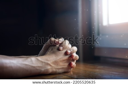 Hands folded in prayer on wooden table with miracle light in church, concept for faith, spirituality and religion, with copy space , space for text