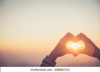 Hands forming a heart shape with sunset silhouette,copy space,warm retro tone. - Shutterstock ID 1006867111