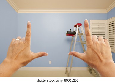 Hands Framing Blue Painted Room Wall Interior With Ladder, Paint Bucket And Rollers.