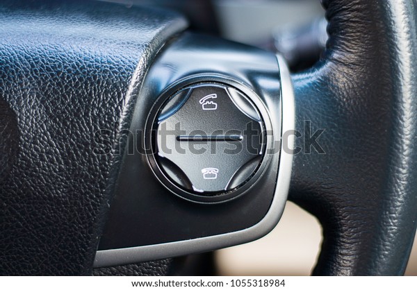 Hands free buttons on the\
steering wheel in black leather, modern car interior details./call\
button