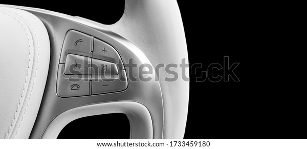 Hands free and media control buttons on the white\
leather steering wheel, modern car interior buttons on the steering\
wheel. Black and white