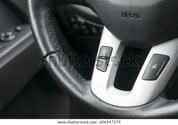 Hands free and media\
control buttons on the steering wheel in black leather, modern car\
interior details