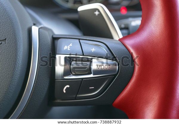 Hands free and media control buttons\
on the red steering wheel in black leather, modern car interior\
buttons on the steering wheel, modern car interior\
details