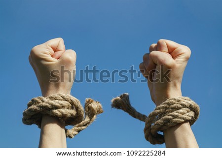 Hands free from shackles are stretched to the blue sky. Feeling of freedom