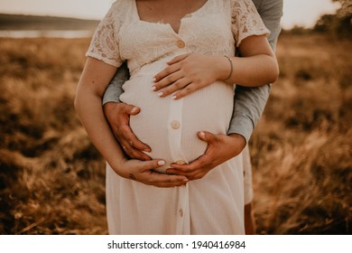 hands of future mother and father clasped pregnant big tummy. husband hugs pregnant wife. Happy family resting in nature hugs in summer at sunset. Caucasian woman in white cotton dress  - Powered by Shutterstock