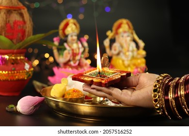 Hands Of Girl Holding Illuminated Clay Diya Deep Dia Lamp With Pooja Thali, Flowers And Doing Aarti Of Maa Lakshmi  Bhagwan Ganesh Deva. Diwali Puja , New Year, Deepawali Or Shubh Deepavali Theme