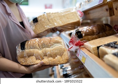 Hands of girl holding sliced white bread product,choosing wheat bread in plastic bag packaged,fresh homemade baked bread in the bakery shop while shopping food,woman buying or selecting food quality