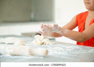 Hands Of Girl Kneading Dough On Kitchen Table With Flour Messy. Kid Baking Buns Or Pies By Herself. Medium Shot. Family Cooking Concept