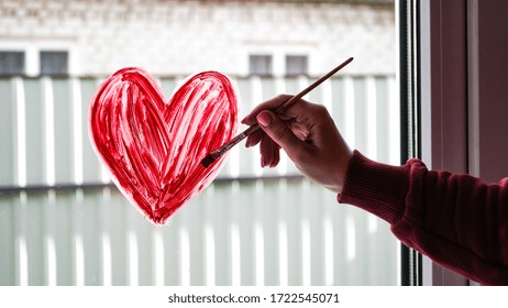 Hands Of A Girl With A Paintbrush Painting Red Heart On A Window, Copy Space For Text, Stay Home, Quarantine Leisure, Let's All Be Well
