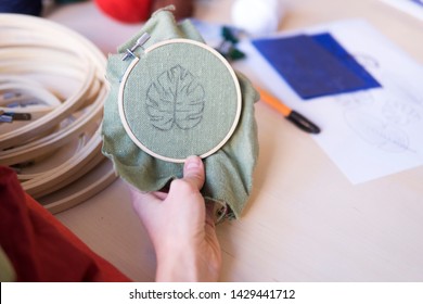 Hands Of Girl/woman/female Sewing Small Embroidery Pattern In A Tiny Wooden Frame, Linen. Needlework Leaf Pattern, Making Chain Stitch, Embroidery Schemes, Frames And Colourful Threads On Background.