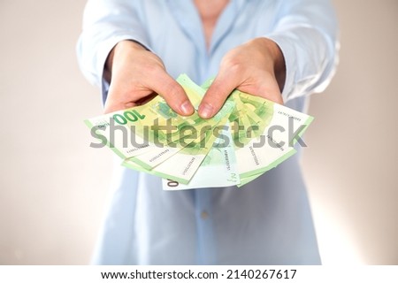 hands giving 100 euro banknotes isolated on light gray background