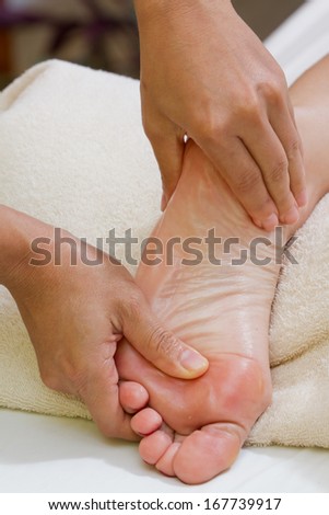 hands giving a foot massage with a white towel on the background