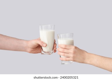 Hands with glasses of milk on grey background - Powered by Shutterstock