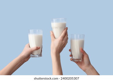 Hands with glasses of milk on light blue background - Powered by Shutterstock