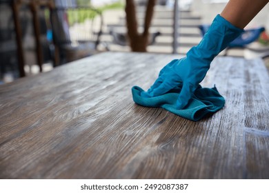 Hands in gloves meticulously clean a wooden surface, demonstrating attention to cleanliness, care, and order - Powered by Shutterstock