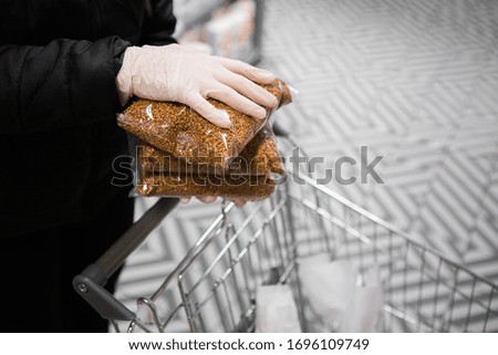 hands in gloves put buckwheat packets in a cart. epidemic safety