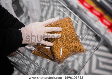 hands in gloves put buckwheat packets in a cart. epidemic safety