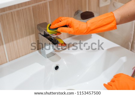 Hands in gloves with rubber cleaning bath faucet