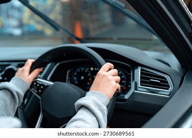 Hands grab the steering wheel while driving at a busy urban location during the day