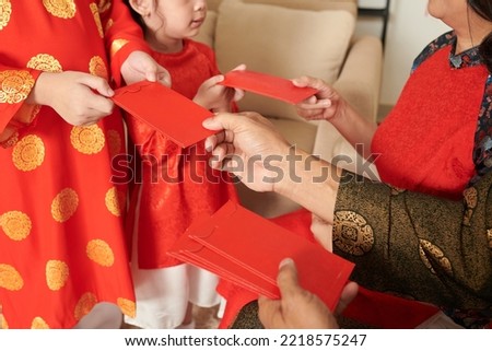 Hands of grandparents gifting lucky money envelopes to children when celebrating Spring festival at home