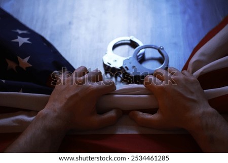 Hands Gripping American Flag with Handcuffs on Wooden Surface - Symbol of Freedom and Justice