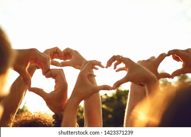 Hands Of Group People In The Shape Of A Heart Against The Sunset.