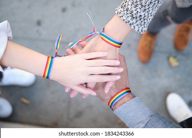 Hands of a group of three people with LGBT flag bracelets. LGBT pride celebration.