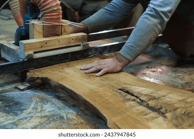 Hands guide wood through a bandsaw, showcasing the art of fine woodworking. It's a blend of control and craftsmanship. - Powered by Shutterstock