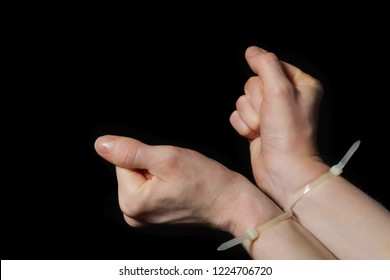 Hands In Handcuffs, Plastic Zip Tie On A Black Background. Big Bruise. Attempt To Break Free From The Shackles. 