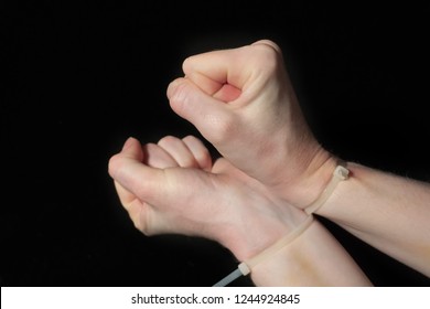 Hands In Handcuffs, Plastic Zip Tie On A Black Background. Fear And Helplessness. 