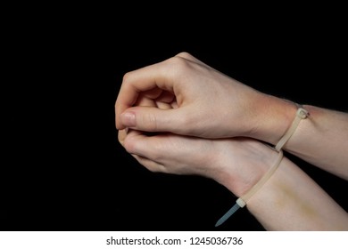 Hands In Handcuffs, Plastic Zip Tie On A Black Background. Fear And Helplessness.