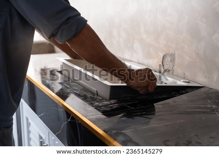 Hands of handyman or worker are placing the sink on the kitchen counter, home renovation and building concept