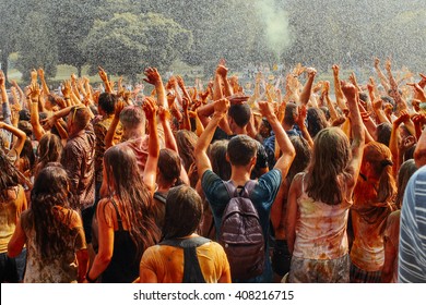 hands and happy people crowd partying under rain at holi fest, festival of colors in summer, amazing moment