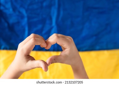 Hands of a heart on the background of the flag Ukraine.  Ukraine against the war.  Stop war in Ukraine.