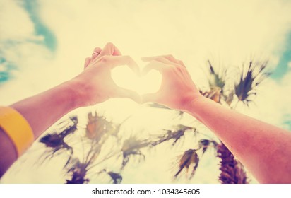 hands in heart shape framing setting sun at sunset on beach - Shutterstock ID 1034345605