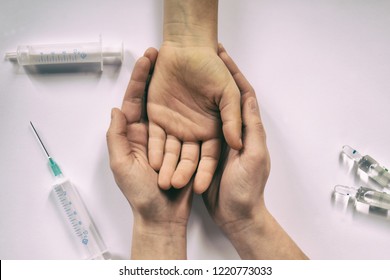 Hands helping drug addict teenage on white background with syringe and ampoules. International Day against Drugs abuse. Stop drug addiction by rehabilitation in rehab center. Trust and ethics concept