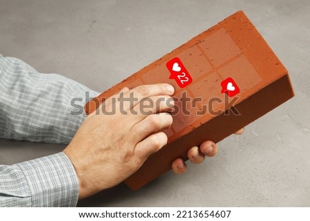 Hands hold brick instead of smartphone and scroll pictures with likes, concept there is no electricity, useless devices