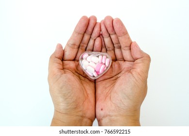 Hands hold a heart case full of heart shape medicines. 