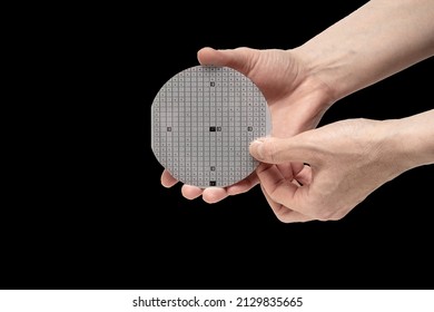 A Hands Hold A Multilayer Semiconductor Silicon Wafer With A Microcircuit Chip Of A Powerful Darlington Transistor Isolated On A Black Background.