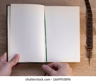 
Hands Hold The Open Closed Book Cover (diary) And A Pen. Wooden Table Background