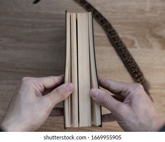 
Hands Hold The Open Closed Book Cover (diary) And A Pen. Wooden Table Background