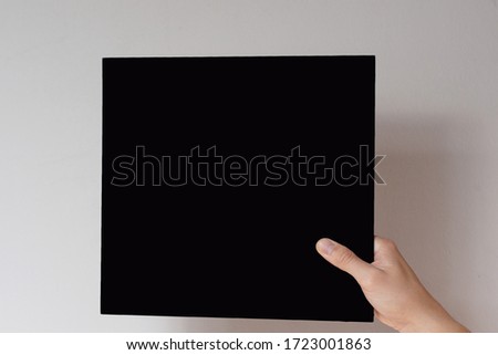 Hands hold a  sheet. Empty space for the label.