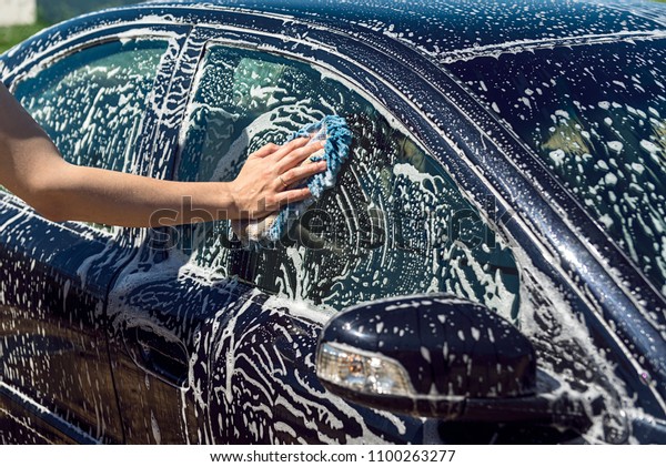hands hold sponge for washing car, man holds\
the microfiber in hand and polishes the car, worker cleaning black\
car, sponge over the car for\
washing,