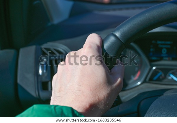 Hands hold the steering wheel of a car, bacteria on\
the steering wheel of a\
car