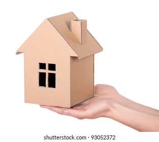 Hands hold a toy house, made of cardboard, isolated on white background