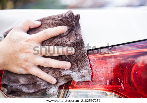 Hands hold washcloth for washing car at car care. A\
man cleaning car with microfiber cloth, detailing Image about\
maintenance of car.