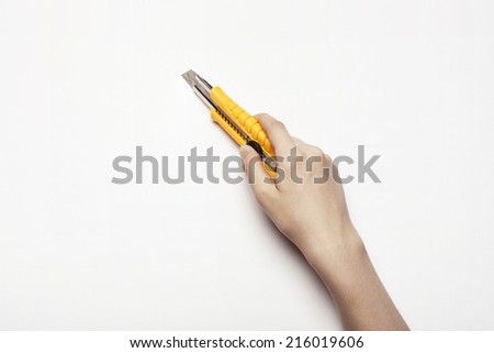 hands hold the yellow cutter knife isolated white.