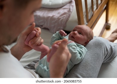 Hands Holding Baby Feet Checking Reflex Of A Newborn.