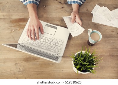 Hands holding bills and paying bills on computer